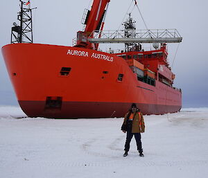 Simon standing in the foreground with Aurora Australis behind him in the ice