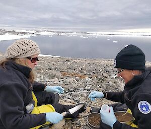 Belindda and Cath in the foreground sampling soil with the water in the background