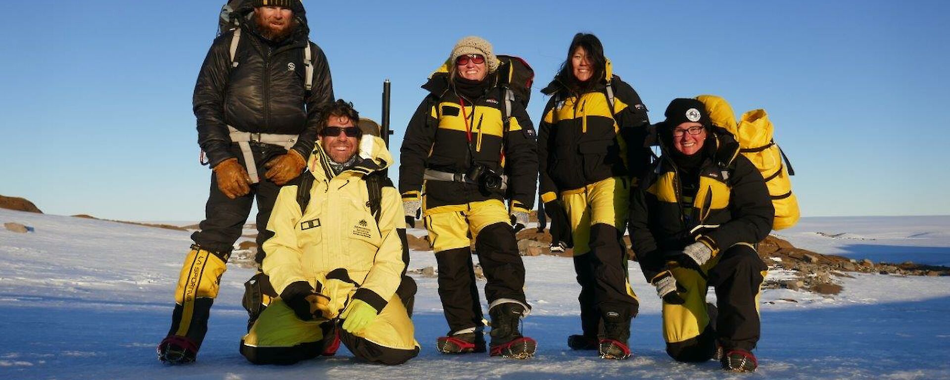 The five members of the Ferrari field team standing on snow together