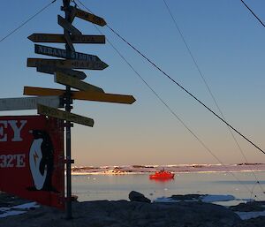 Casey sign in the foreground with Aurora Australis in the bay in the background