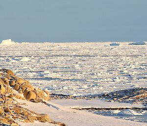 The ice of the bay with icebergs in the background