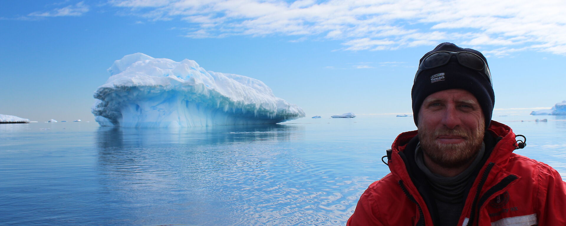 Scott driving the boat with an iceberg in the background