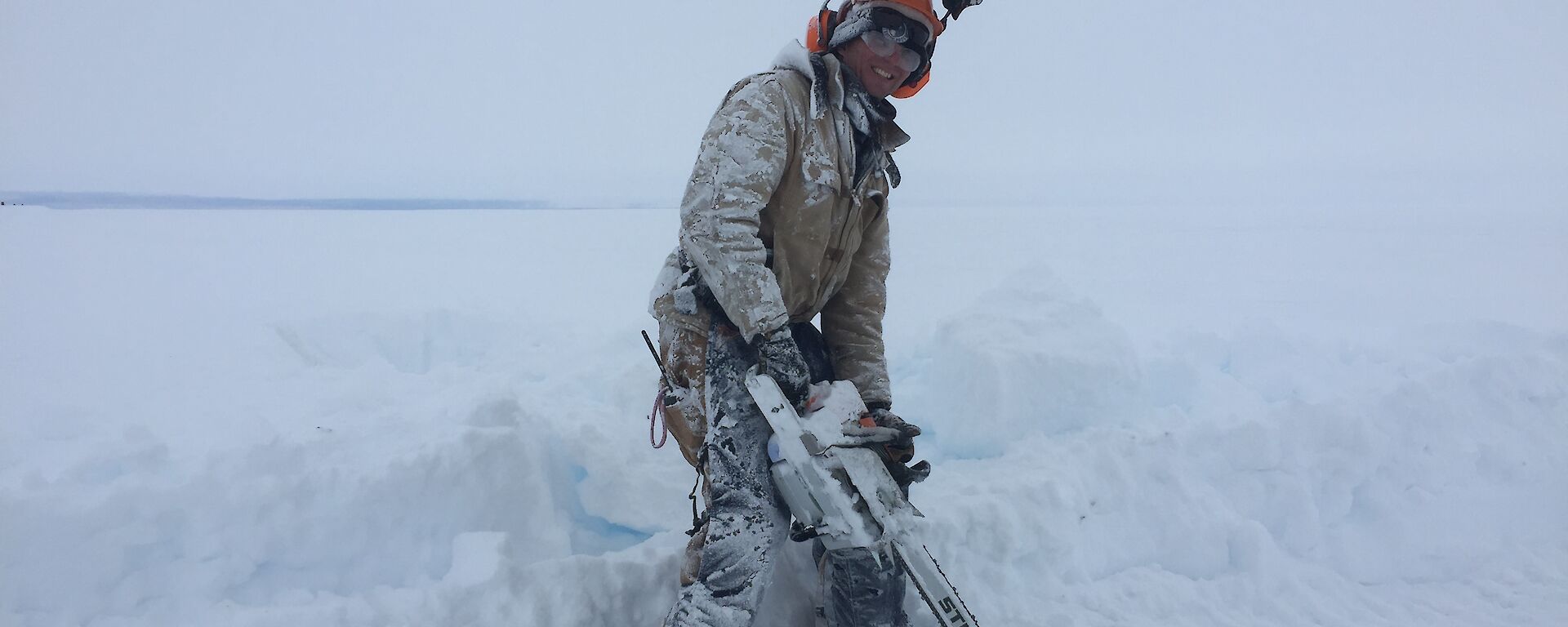 Conrad cutting into the ice with a chainsaw
