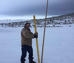 Ryhs looking up at the cane standing on snow with rocks in the background