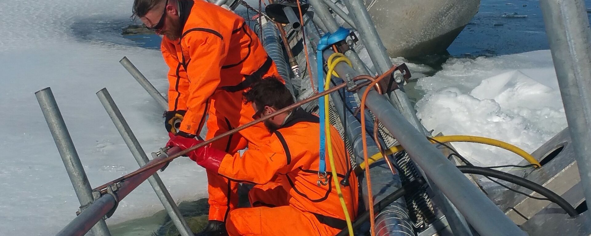 Two tradies in floatation suits on the melt bell pontoon