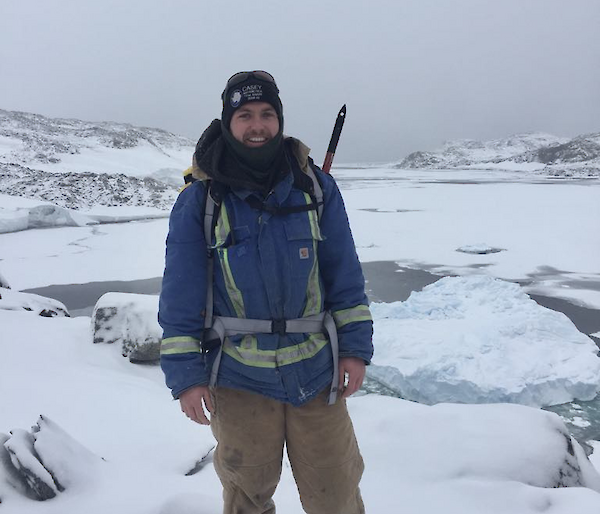 Aaron standing in his field gear with snow and ice in the background
