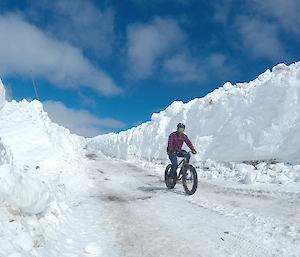 aaron riding a mountain bike with fat tyres down wharf road with snow walls