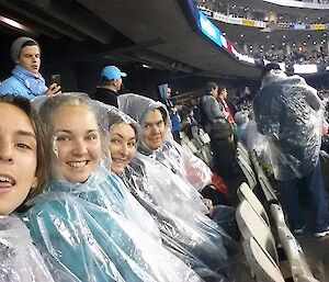 Ethan, Samantha, Kathy with Leigh at the MCG wearing rain covers