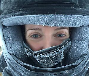 A close up of Amy during sea ice travel showing her face, helmet with a covering of frost