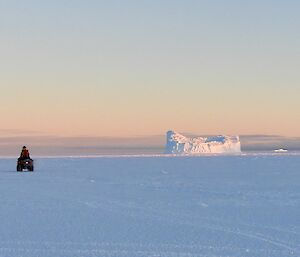 Riding on the sea ice with one quad and an ice berg in the frame