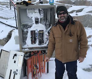SCott standing next to a switchboard filled with snow after a blizz