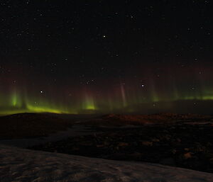 An aurora across the horizon of green and red