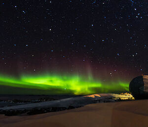 A green aurora across the sky with ANARESAT dome in the foreground