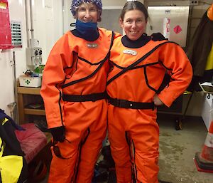 Tanya and Chris all dressed in orange dry suits standing in the wharf hut before heading out on the ice