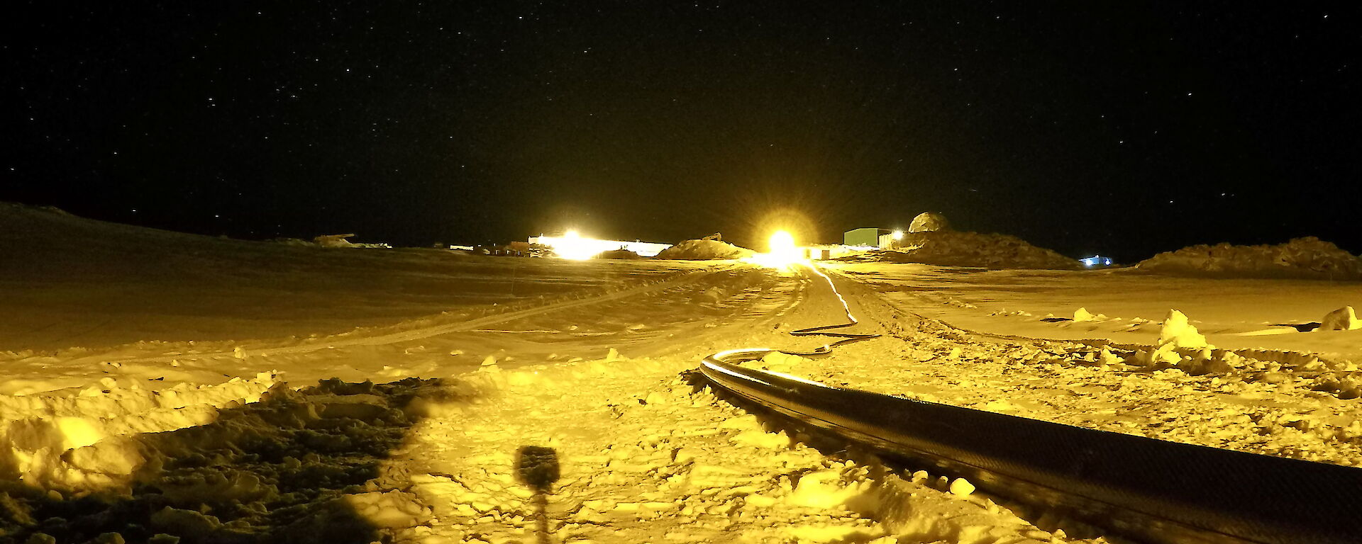 A long black hose lying across the snow with the Station in the background