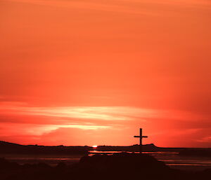 The sun slipping below the horizan with Reeve’s Hill and the cross in the foreground