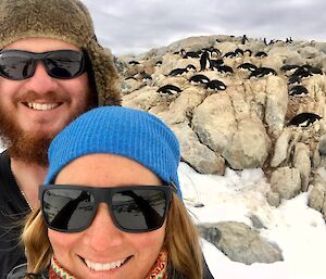 Jords and James visiting the penguins of Shirley Island during the summer with Jordan and James in the foreground and penguins on rocks behind