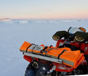 A quad on the ice with ice cliffs in the background