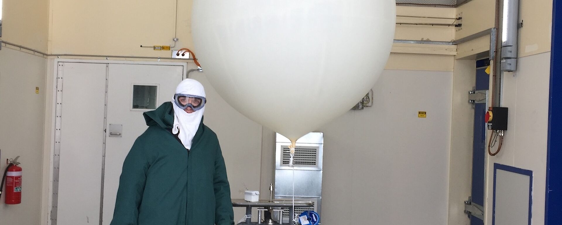 Even dressed in a green smock and head cover and goggles with an inflated weather balloon