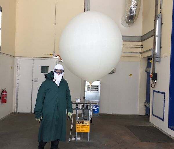 Even dressed in a green smock and head cover and goggles with an inflated weather balloon