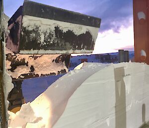 A dozer clearing snow from the open workshop door