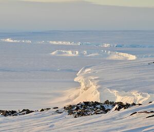 A coastal shot of the ice cliffs with rocks