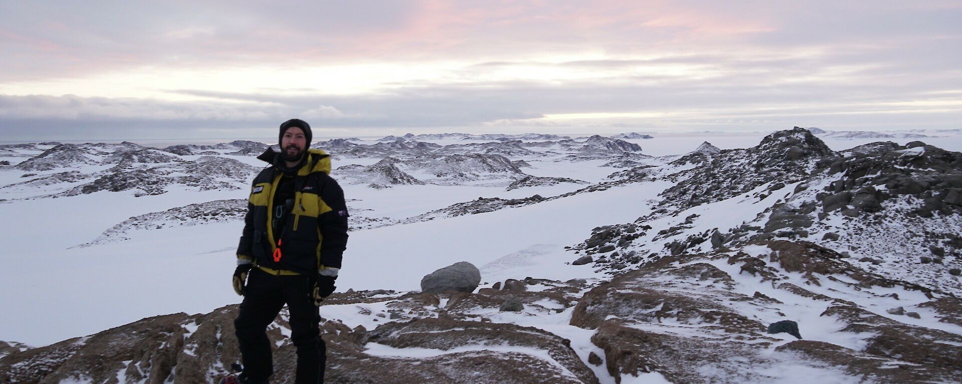 Juan standing on rocks with snow, rocks and ice in the background