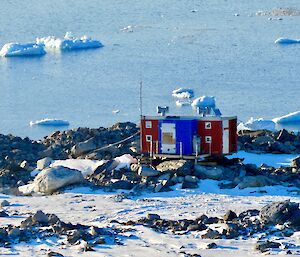 Jack’s Donga which is red and blue sitting on rocks overlooking icebergs and the water