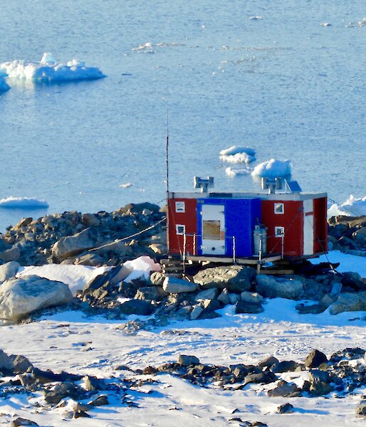 Jack’s Donga which is red and blue sitting on rocks overlooking icebergs and the water