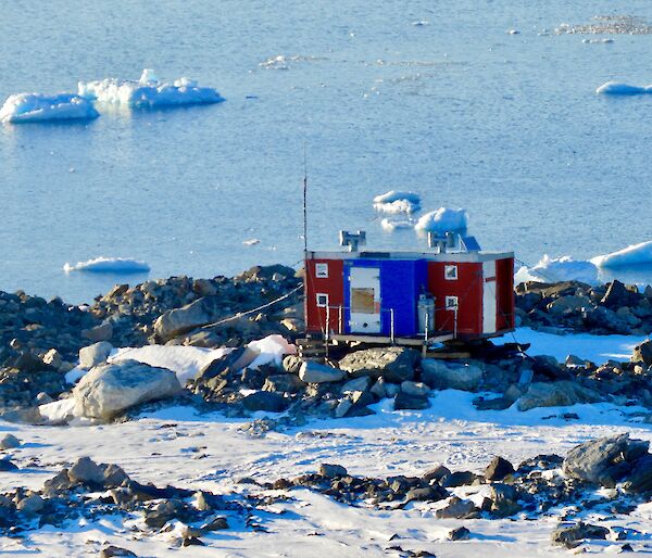 Jack’s Donga which is red and blue sitting on rocks overlooking icebergs and the water
