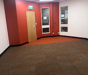 Inside the Red Shed in the library with red and off white walss with new rust, orange carpet