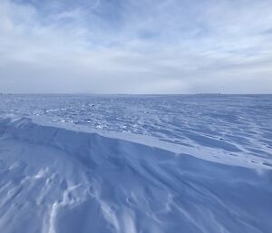 Lots of snow covering up the ice runway on a partly cloudy day