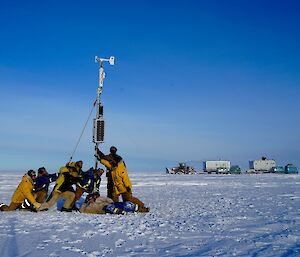 The Traverse team posing near the AWS with vehicles in the back ground on a snow white surface