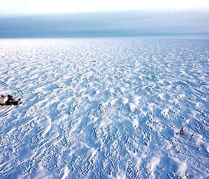 A drone shot of the traverse group of vehicles and the Automsted Weather System being worked on surrounded by snow and a grey sky