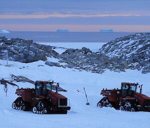 Two quadtracs in the foreground with rock, ice and icebergs in the background