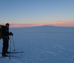 Garvan on Skis looking at the camera on the sea ice with the sun on the snow behind him