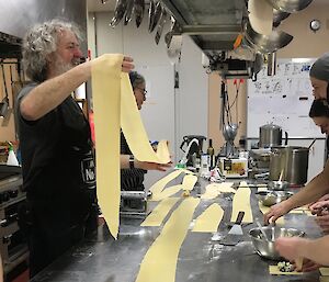 Multiple sheets of pasta being laid out in the kitchen