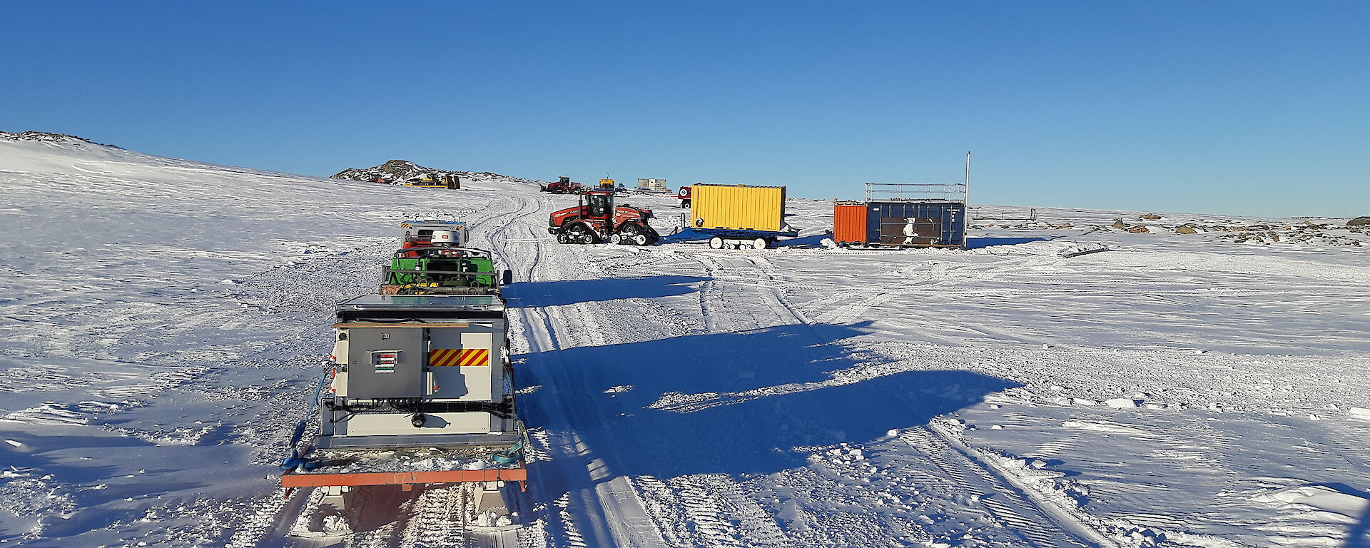 Several vehicles towing trailers departing Station on a sunny, clear day