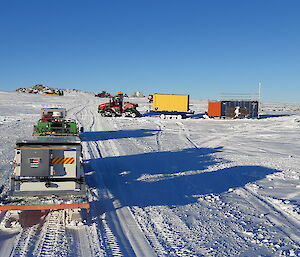 Several vehicles towing trailers departing Station on a sunny, clear day