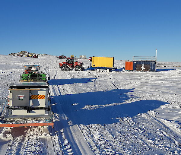 Several vehicles towing trailers departing Station on a sunny, clear day