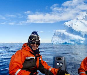 Chris steering the small boat on the water with icebergs in the background