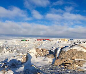 A sunny Casey with the Red Shed, Green Store, Yellow Science building surrounded by snow