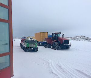 Tractor with trailer amd green hagg ready to leave Casey on a snowy day