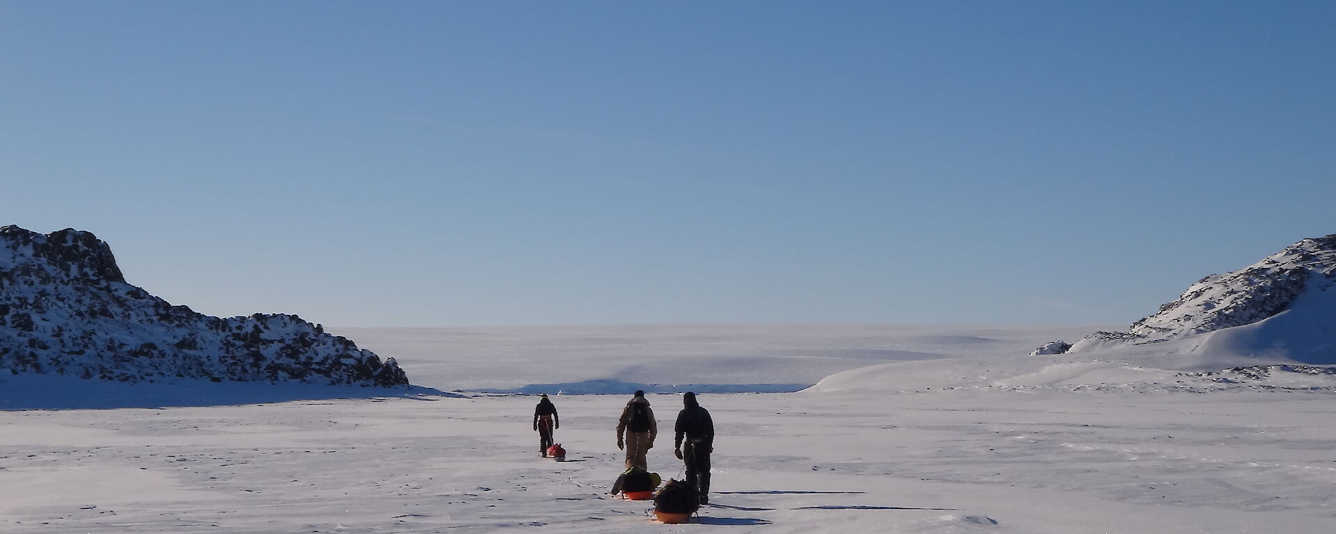 Three expeditioners hauling sleds on the sea ice