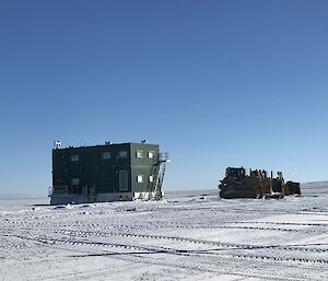 A dozer towing the green Wilkins mess building into the summer location