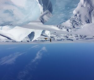 One expeditioner walking on the sea ice with lots of small ice bergs and snow drifts