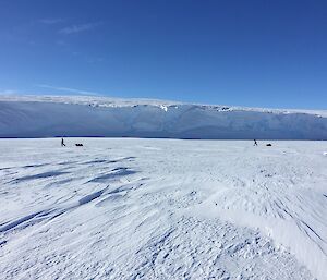 Two expeditioners walking in front of the ice cliffs on Penny Bay