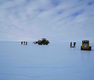 Two machines and a team conducting runway repairs on the ice runway