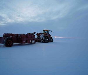 A red proofroller, working on the ice runway under a cloudy sky