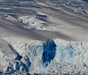 Snow and ice of ice cliffs under a blue sky